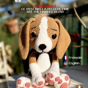 May include: A handmade crochet beagle plush toy, featuring brown, white, and black details. The text on the image reads "Baloo - le petit beagle / the little beagle" and "CE N'EST PAS LA PELUCHE FINIE NOT THE FINISHED PLUSH". The toy has pink paw pads.