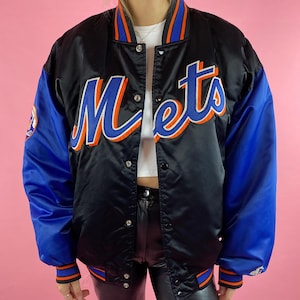 Op de afbeelding: Zwarte satijnen jas met blauwe mouwen en het woord "Mets" in oranje en blauw script over de borst. De jas heeft een drukknoopsluiting, geribde manchetten en een kraag met oranje en blauwe strepen.