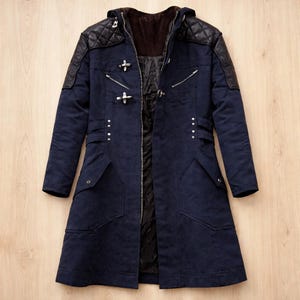 Könnte beinhalten: Ein marineblauer Mantel mit Kapuze und schwarzen, gesteppten Schulterakzenten. Der Mantel hat einen Reißverschluss, dekorative Verschlüsse und mehrere Taschen. Das Innenfutter ist dunkelbraun.