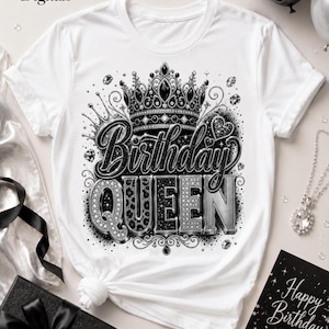 May include: A white t-shirt featuring a black and silver graphic of a crown above the text Birthday QUEEN. The design includes leopard print, glitter, and diamond-like accents. The shirt is displayed with a black gift box and a silver necklace.