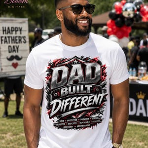 Peut inclure: Un t-shirt blanc à manches courtes avec un motif graphique portant le texte DAD BUILT DIFFERENT en lettres métalliques grasses. Sous le texte figurent les mots LEADER, PROTECTOR, PROVIDER, STRONG, RESPECTED, DEDICATED, DEPENDABLE, FEARLESS, LEGENDARY, HARDWORKING.