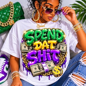 May include: A white t-shirt featuring a graphic print with the text SPEND DAT SHIT in green, yellow, and purple bubble letters. The design includes illustrations of 100 dollar bills, a gold chain, and a gold dollar sign pendant with purple drips.