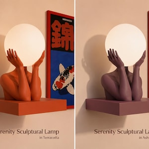 Puede incluir: Dos l&aacute;mparas esculturales Serenity, una en terracota y otra en morado ceniza. Cada l&aacute;mpara presenta un torso humano y manos que sostienen un globo de luz esf&eacute;rico blanco. La base es un estante rectangular. Texto: Serenity Sculptural Lamp.