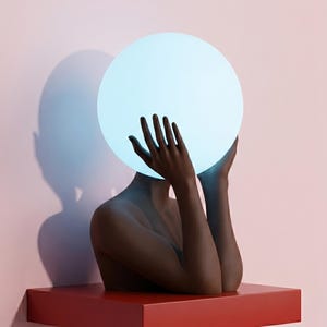 May include: A dark chocolate colored sculptural lamp featuring a torso with raised hands holding a glowing, circular, light blue orb. The base is a rectangular red platform. The text "Serenity Sculptural Lamp in Dark Chocolate" is printed below.