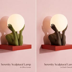 Puede incluir: Dos l&aacute;mparas esculturales Serenity sobre estantes rojos. Una l&aacute;mpara presenta una figura verde oliva que sostiene una bombilla esf&eacute;rica blanca brillante, y la otra una figura marr&oacute;n chocolate oscuro con una bombilla esf&eacute;rica blanca a juego.