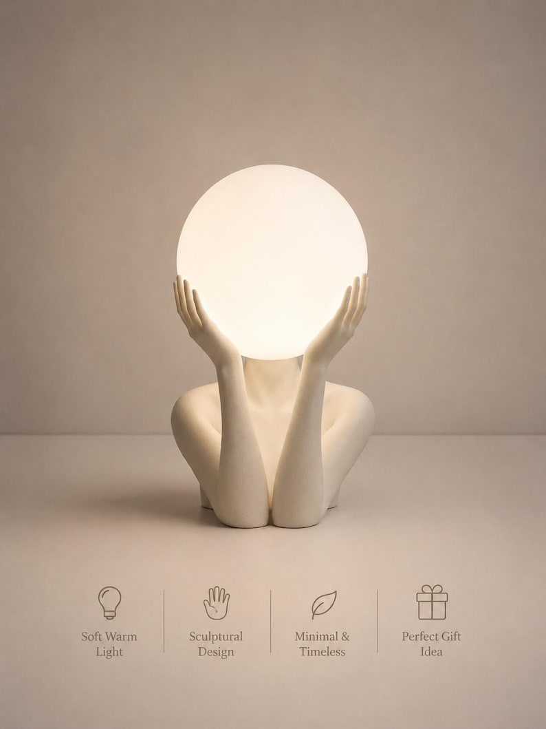 Puede incluir: Una l&aacute;mpara de mesa escultural blanca que muestra un torso y brazos humanos alzados para sostener una bombilla esf&eacute;rica brillante. Debajo de la l&aacute;mpara, cuatro iconos se muestran con el texto: Soft Warm Light, Sculptural Design, Minimal & Timeless, Perfect Gift Idea.