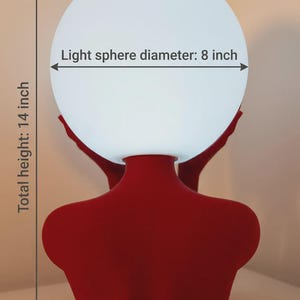 Puede incluir: Una base de l&aacute;mpara con forma de busto rojo que sostiene un globo de luz esf&eacute;rico blanco. El texto en la imagen indica un di&aacute;metro de esfera de luz de 8 pulgadas y una altura total de 14 pulgadas. La l&aacute;mpara tiene un acabado rojo mate.