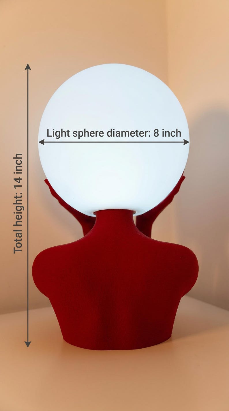 May include: A red lamp base shaped like a human torso supporting a white spherical light. The text on the image indicates a light sphere diameter of 8 inches and a total height of 14 inches. The lamp features a matte red finish and a smooth texture.