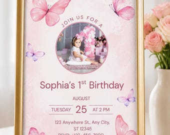 Puede incluir: Una invitación con marco dorado para el primer cumpleaños de Sophia con mariposas de acuarela rosa, una foto circular de un niño y texto que detalla la fecha, hora, ubicación y número de teléfono RSVP sobre un fondo rosa claro.