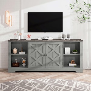 May include: A gray wooden TV stand with a dark brown top. The stand has two doors with an X design and open shelves on either side. A TV is mounted above the stand, and decorative items are displayed on the shelves.