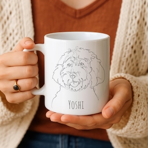 Könnte beinhalten: Ein weißer Keramikbecher mit einer schwarzen, durchgehenden Strichzeichnung eines lockigen Hundes. Unter der Hundeillustration ist der Name YOSHI in einer einfachen, klaren, schwarzen serifenlosen Schrift gedruckt. Der Becher hat eine glatte Oberfläche.