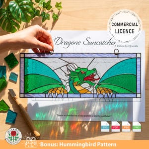 Könnte beinhalten: Ein rechteckiges Buntglasfenster mit einem grünen Drachen mit roten Akzenten. Das Panel trägt die Aufschrift "Dragone Suncatcher" und enthält ein "Commercial Licence"-Abzeichen. Das Bild enthält auch ein Bonus-Kolibri-Muster.