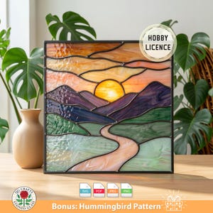 May include: Stained glass panel depicting a sunset over mountains and a winding river. The artwork features a vibrant color palette of orange, purple, green, and blue, with a black metal frame. Includes a "Hobby Licence" and "Bonus: Hummingbird Pattern" text.