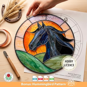 Op de afbeelding: Rond glas-in-lood kunstwerk met een zwart paard tegen een zonsondergang en groene heuvels. De afbeelding bevat een hoefijzer, tarwe en knutselbenodigdheden. Het ontwerp is gelabeld als een 'Beginner Black Horse' patroon.