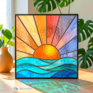 Könnte beinhalten: Buntglasfenster mit einem Sonnenuntergang über dem Meer. Die Sonne ist leuchtend orange, mit gelben, orangen und roten Strahlen. Das Meer ist blau und türkis. Das Panel ist schwarz umrahmt. Text: By: QGCrafts.