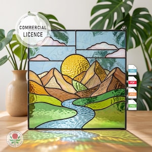 Op de afbeelding: Gebrandschilderd glaspaneel met een berglandschap met een gele zon, blauwe rivier en groene velden. Het paneel heeft een zwart frame en de tekst "COMMERCIAL LICENCE" en "QG CRAFTS STAINED GLASS".