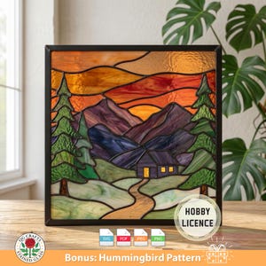 May include: Stained glass panel showing a mountain scene with a cabin, trees, and a sunset. The artwork has a black frame and a warm colour palette of orange, purple, and green. Includes the text "Bonus: Hummingbird Pattern".