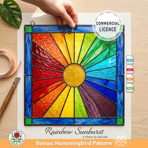 May include: A stained glass panel featuring a rainbow sunburst design. The artwork has a central yellow circle with radiating segments of red, orange, yellow, green, blue, and purple. The panel is framed in blue and black. Text on the image reads "Rainbow Sunburst".