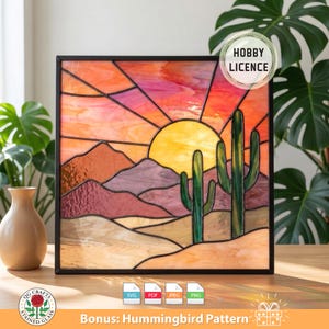 Op de afbeelding: Gebrandschilderd kunstwerk dat een woestijnzonsondergang toont met een gele zon, bergen en cactussen. Het stuk is zwart omlijst en gebruikt oranje, roze en groene kleuren. De afbeelding bevat de tekst "Hobby Licence".