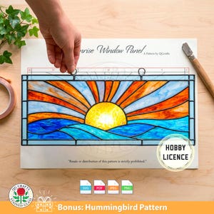 Peut inclure: Panneau de fenêtre en vitrail représentant un lever de soleil sur des vagues bleues. Le soleil est jaune vif, avec des rayons orange et bleus. Le panneau est rectangulaire avec un cadre noir. Texte : "Sunrise Window Panel" et "Bonus: Hummingbird Pattern".