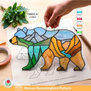 Può includere: Un orso in vetro colorato con un design a paesaggio montano nei toni del blu, verde e arancione. L'orso è tenuto in mano. L'immagine include il testo "COMMERCIAL LICENCE" e "Bonus: Hummingbird Pattern".