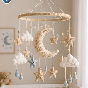 Può includere: Una giostrina sospesa con una grande mezzaluna all'uncinetto color beige, circondata da stelle più piccole all'uncinetto color beige e azzurro, nuvole bianche e piccole gocce di pioggia azzurre, appese a una cornice circolare rivestita di filo.