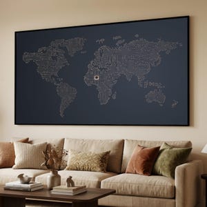 May include: A framed world map artwork featuring a circuit board design. The map is depicted with light lines on a dark blue backdrop. The artwork hangs above a beige sofa with various cushions, creating a modern aesthetic.