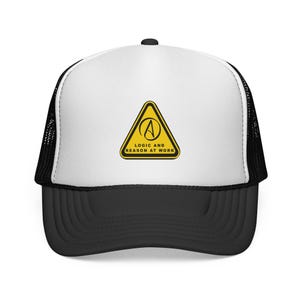 Könnte beinhalten: Schwarz-weiße Trucker-Cap mit weißem Frontpanel. Die Kappe zeigt ein gelbes Dreieck mit einem stilisierten "A"-Symbol und dem Text "LOGIC AND REASON AT WORK". Der Schirm ist schwarz.