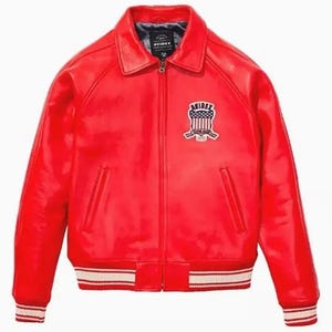 May include: A vibrant red leather jacket with a collared neckline and a zip-up front. The jacket features a patch on the chest with an emblem and white and red striped detailing on the cuffs and hem. The jacket has two front pockets.