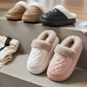 May include: A collection of quilted house slippers in various colors, including tan, black, white, and pink. Each slipper features a plush, faux fur lining and trim. The slippers have a bear emblem on the front.