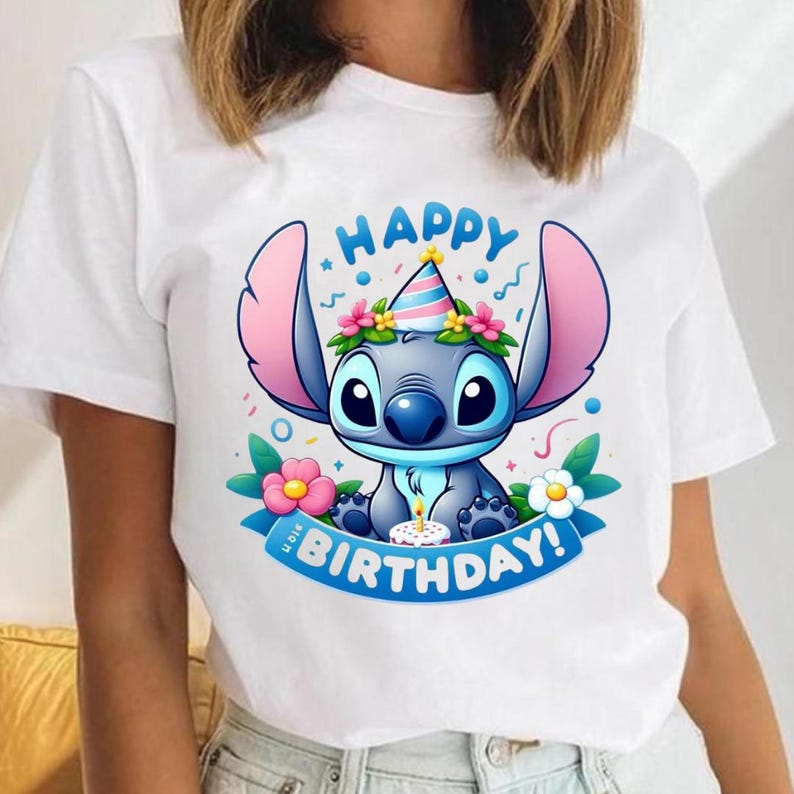 May include: White t-shirt featuring a cartoon character with large ears, wearing a party hat and surrounded by flowers. The design includes the words "HAPPY BIRTHDAY!" on a blue banner.