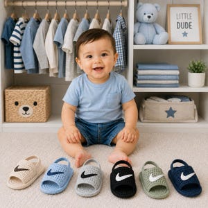 May include: A set of six crochet baby sandals in various colors including beige, light blue, gray, black, sage green, and navy blue. Each sandal features a prominent Nike swoosh logo on the top strap and a back heel strap for a secure fit.