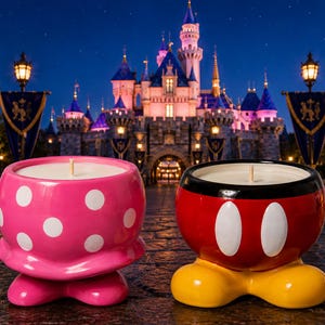 May include: Two ceramic candle holders shaped like cartoon character bottoms. One is pink with white polka dots and pink feet, while the other is red with a black top rim, two white oval buttons, and yellow shoes. Both contain white wax and a single wick.
