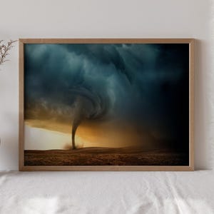Op de afbeelding: Een ingelijste print met een dramatische afbeelding van een tornado. Het kunstwerk toont een wervelende wervelwind tegen een achtergrond van donkere, onheilspellende wolken en een gouden, zonovergoten horizon. De print wordt op een wit oppervlak gepresenteerd.