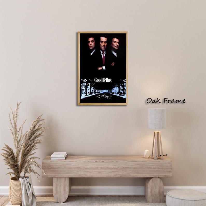 May include: A framed poster featuring the movie "Goodfellas." The poster showcases three men in suits against a dark background. The title "GoodFellas" is displayed in white text at the bottom, with a street scene illustration.
