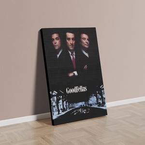 May include: A canvas print featuring the movie poster for "Goodfellas." The artwork showcases three men in suits against a dark background. The title "Goodfellas" is displayed at the bottom, with a city scene illustration.