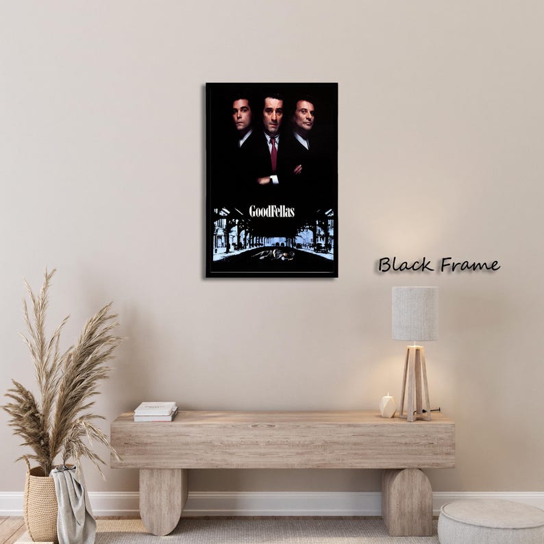 May include: A framed movie poster for the film "Goodfellas" featuring three men in suits. The poster has a black frame and the title is displayed at the bottom. The background is a dark, stylized image of a street.