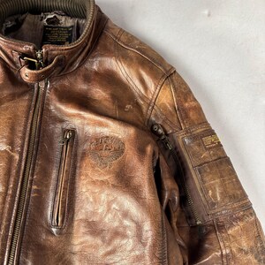 K&ouml;nnte beinhalten: Eine wei&szlig;e Keramik-Tasse mit schwarzem Henkel und dem Text "But First, Coffee" in fetter, schwarzer Schrift. Die Tasse steht vor einem verschwommenen Hintergrund, der eine gem&uuml;tliche Umgebung suggeriert.