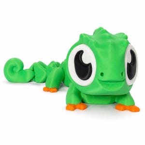 May include: A bright green articulated lizard figurine featuring large white eyes with black pupils and small orange feet. The creature has a textured, segmented body that curves toward the back, ending in a curled tail, with a smooth finish.