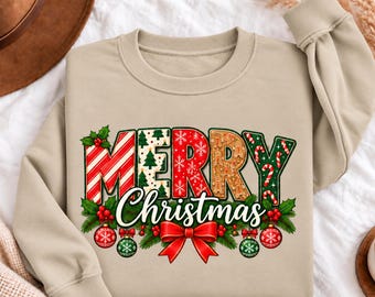 May include: A beige crewneck sweatshirt featuring the text Merry Christmas in large, colorful letters. The letters are decorated with candy cane stripes, pine trees, snowflakes, and gingerbread men. Below the text are red bows and ornaments.
