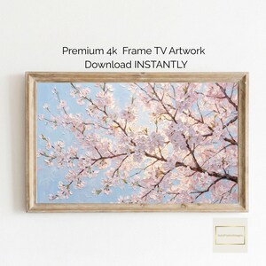May include: A framed artwork featuring a close-up of a cherry blossom tree in full bloom. The painting has a light blue sky background and the blossoms are pink and white. The frame is a light brown color. The text "Premium 4k Frame TV Artwork Download INSTANTLY" is at the top.