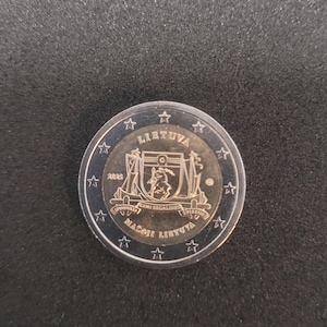 Könnte beinhalten: Eine Zwei-Euro-Münze aus Litauen, datiert 2023, mit detailliertem Design. Die Münze zeigt das Wort "LIETUVA" oben, ein Wappen in der Mitte und die Worte "MAŽOJI LIETUVA" unten. Die Münze hat ein silbernes und goldenes Farbschema.