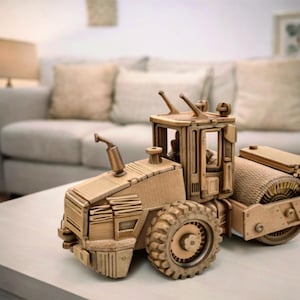 May include: A detailed wooden model of a road roller, featuring a cabin, large wheels, and a rolling drum. The model is constructed from light brown wood and sits on a white surface.