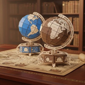May include: Two wooden globe models, one blue and one brown, sit on a map-covered desk. The globes are intricately designed with visible continents. A quill and inkwell are on the desk, along with a rolled-up map, suggesting a study or library setting.