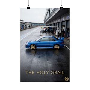 May include: A blue sports car with gold rims is parked on a wet track. The image is a poster with the text "THE HOLY GRAIL" in gold lettering at the bottom. The car has a spoiler and is in front of a garage.