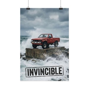 Könnte beinhalten: Ein roter Pickup-Truck steht auf einer Betonkonstruktion, umgeben von Wellen unter einem stürmischen Himmel. Das Wort "INVINCIBLE" ist in einem schwarzen Stempel am unteren Bildrand aufgedruckt.