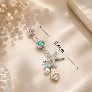 May include: A silver belly button ring with a blue gem, a starfish charm, and dangling beads and a seashell. The total length of the ring is 5.4 cm.