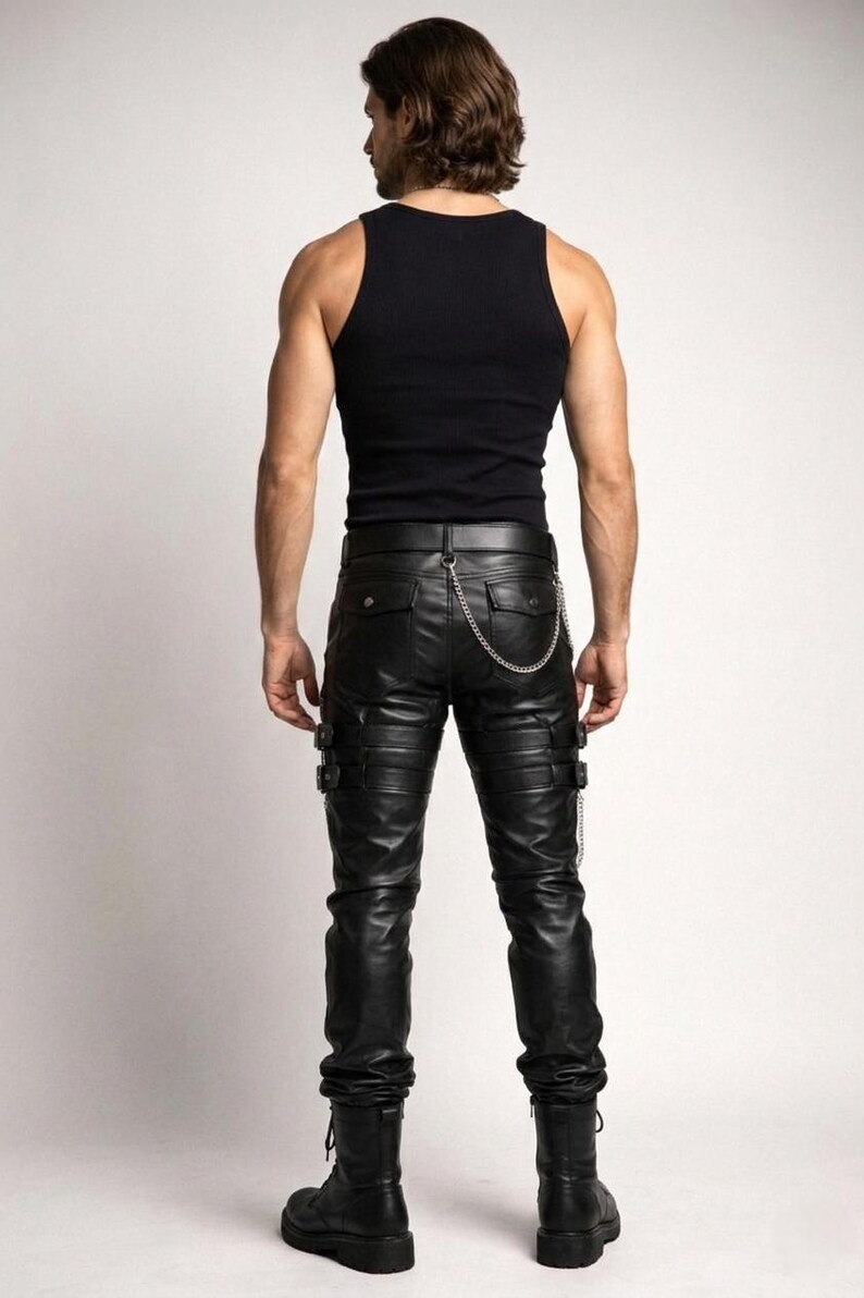 May include: Black leather pants with multiple buckles and a silver chain detail. The pants have a ribbed design on the knees and pockets on the back. Paired with a black tank top and black boots.