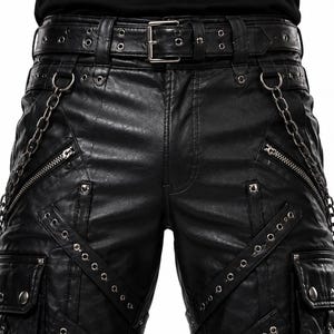 Puede incluir: Pantalones negros de cuero sintético con múltiples bolsillos, cremalleras y detalles de ojales metálicos. Los pantalones cuentan con un cinturón a juego con una hebilla plateada y una cadena plateada sujeta a la cintura. Los pantalones tienen una apariencia texturizada.