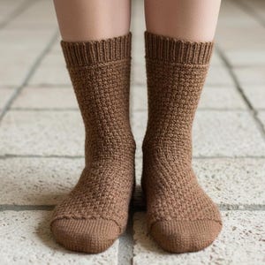 May include: A pair of brown knitted socks. The socks are a medium brown colour with a textured pattern. The ribbed cuffs and toes are a slightly darker shade of brown. The socks are worn on a person's legs.